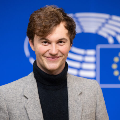 Malte Gallée vor einer blauen Wand mit Logo des Europäischen Parlaments