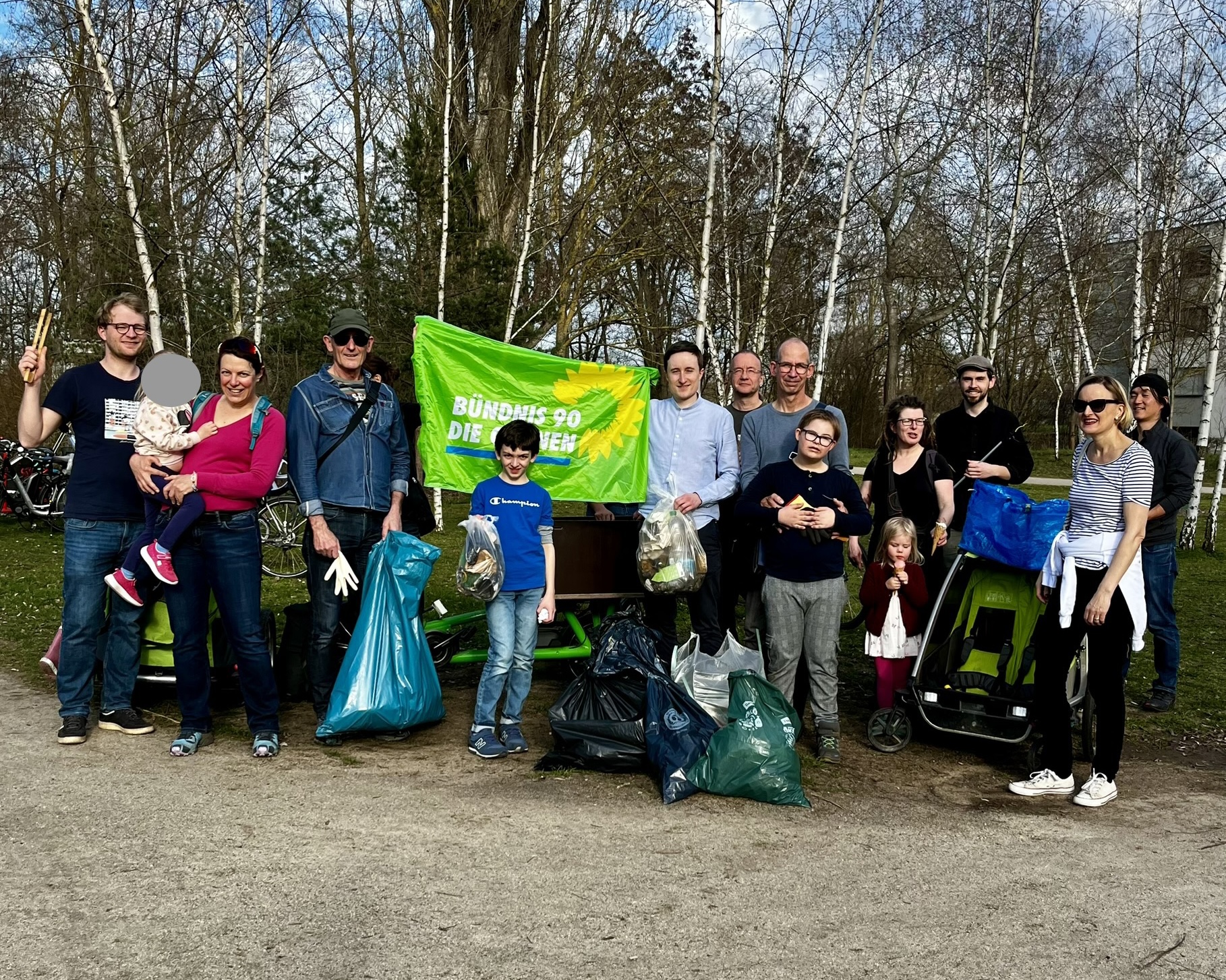 Grüne Müllsammler:innen mit Parteifahne und Säcken mit gesammeltem Müll